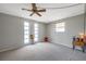 Bedroom with gray carpet, three windows, a ceiling fan, and a small end table at 7035 Cutty Sark Dr, Port Richey, FL 34668