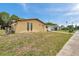A cozy yellow home featuring a well-maintained lawn and a sunny sky backdrop at 7035 Cutty Sark Dr, Port Richey, FL 34668