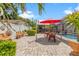 Back patio features a bright red umbrella, potted palms, and outdoor seating for relaxed enjoyment of the pool view at 713 715 W Fribley St, Tampa, FL 33603