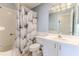 A well-lit bathroom features neutral-toned tile, a shower, vanity and mirror offers comfort and convenience at 7499 Blue Skies Dr, Spring Hill, FL 34606