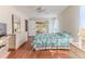 Sunlit bedroom featuring wood floors, a tropical-themed bedspread, and access to the lanai at 7499 Blue Skies Dr, Spring Hill, FL 34606