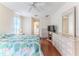 Bright bedroom with floral bedding, wood floors, and dresser with a large mirror at 7499 Blue Skies Dr, Spring Hill, FL 34606