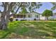 Well-maintained exterior with screened patio surrounded by a lush lawn, mature shade trees, and meticulous landscaping at 7499 Blue Skies Dr, Spring Hill, FL 34606