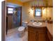 Well-lit bathroom featuring a glass-enclosed shower, tile flooring, and wooden vanity at 8126 Wooden Dr, Spring Hill, FL 34606