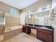 Primary bathroom featuring double vanity sinks, separate tub and shower, and tiled flooring at 9124 Topneck St, New Port Richey, FL 34654