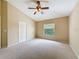 Spacious bedroom with neutral carpet, a ceiling fan, and a large window allowing for natural light at 9124 Topneck St, New Port Richey, FL 34654