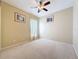 A bright, carpeted bedroom featuring neutral walls, a ceiling fan, and a large window at 9124 Topneck St, New Port Richey, FL 34654