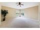 A large bedroom with neutral carpet, a ceiling fan, two big windows, and tan-colored walls at 9124 Topneck St, New Port Richey, FL 34654