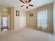 Spacious bedroom with neutral carpet, a ceiling fan, closet, and a view to the home's entrance at 9124 Topneck St, New Port Richey, FL 34654