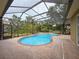 Screened-in pool area with uniquely shaped pool, waterfall feature, and brick patio at 9124 Topneck St, New Port Richey, FL 34654