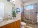 Bathroom featuring tile shower with glass door, granite counters, and wood cabinets at 9125 Palm Beach Dr, Brooksville, FL 34613
