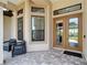 Inviting covered front porch with tiled floor, glass double doors and matching chairs for relaxing at 9125 Palm Beach Dr, Brooksville, FL 34613