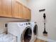 Laundry room equipped with washer, dryer, overhead cabinets and a mounted vacuum at 9125 Palm Beach Dr, Brooksville, FL 34613