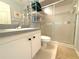 A well lit bathroom featuring a shower with glass doors, vanity, sink, and toilet at 9311 Haas Dr, Hudson, FL 34669