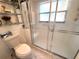 Bright bathroom features a toilet, shelving, and walk-in shower with textured sliding doors at 9311 Haas Dr, Hudson, FL 34669