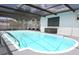 Inviting in-ground pool enclosed with screen, featuring steel ladder, and a covered patio at 9942 Woodridge Ct, Port Richey, FL 34668