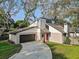 Charming two-story home with a unique architectural design, stucco siding, a red front door, and an attached two-car garage at 10910 Winter Oak Pl, Tampa, FL 33618