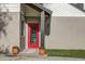 Close up on the red front door, featuring well maintained stucco and a beautifully landscaped garden at 10910 Winter Oak Pl, Tampa, FL 33618