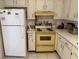Well-lit kitchen featuring white cabinets, yellow oven, and tile flooring at 11224 Yewtree Ave, Port Richey, FL 34668