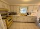 Bright kitchen featuring white cabinets, a vintage yellow stove, and white countertops at 11224 Yewtree Ave, Port Richey, FL 34668