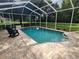 Inviting screened-in pool with light blue water, stone surround, and comfortable outdoor seating on the patio at 12270 Clarendon Ct, Spring Hill, FL 34609