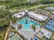 A high-angle view of a community center with pools, tennis courts, shuffleboard and lounge areas surrounded by parking and trees at 16793 Forge Surf St, Land O Lakes, FL 34638