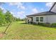 Large grassy backyard with small bushes and trees with a covered patio on the home at 16793 Forge Surf St, Land O Lakes, FL 34638