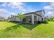 View of covered patio in a grassy backyard with a grill and a flamingo lawn ornament at 16793 Forge Surf St, Land O Lakes, FL 34638