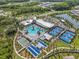 An aerial shot reveals a community center with a large pool, tennis courts, and ample parking surrounded by trees at 16793 Forge Surf St, Land O Lakes, FL 34638