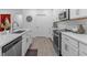 Bright kitchen features white cabinets, stainless steel appliances, and wood-look tile flooring at 16793 Forge Surf St, Land O Lakes, FL 34638