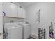 Functional laundry room with a washer, dryer, white cabinets for storage and gray walls at 16793 Forge Surf St, Land O Lakes, FL 34638