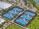 Bird's-eye view of a tennis court area in community featuring multiple courts, landscaping, and parking at 16793 Forge Surf St, Land O Lakes, FL 34638