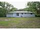 The backyard of the house showing the exterior wall, sliding glass door, and windows at 18838 Rosephil St, Spring Hill, FL 34610