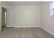 A bright bedroom with a white door and light hardwood floors features a window with natural light at 18838 Rosephil St, Spring Hill, FL 34610