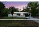 Charming single-story home with a well-maintained lawn, mature trees, and freshly painted exterior at dusk at 18838 Rosephil St, Spring Hill, FL 34610