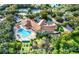 Aerial view showcasing a pool, clubhouse, tennis court, bocce ball, and lush landscaping at 261 Rochester St, Spring Hill, FL 34609