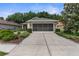 Charming single-story home featuring a screened garage, concrete driveway, and landscaped front yard at 261 Rochester St, Spring Hill, FL 34609