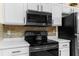 Clean kitchen with white cabinets, backsplash and sleek black appliances at 261 Rochester St, Spring Hill, FL 34609