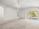 Open-concept living room featuring neutral carpeting, a modern ceiling fan, and sliding glass doors to the patio at 3885 Crossline Dr, Spring Hill, FL 34609