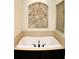 Large soaking tub with tiled accent wall in neutral bathroom at 4837 Rainbow Race, New Port Richey, FL 34652