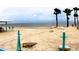 Sandy beach featuring multiple cornhole boards, lounge chairs, palm trees, and serene ocean views at 4837 Rainbow Race, New Port Richey, FL 34652
