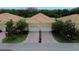 Charming two-unit villa featuring a yellow exterior, tile roof, and brick-paved driveway leading to attached garages at 4837 Rainbow Race, New Port Richey, FL 34652