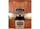 Close-up of the kitchen stove and microwave, complemented by granite countertops and a tiled backsplash for a modern look at 4837 Rainbow Race, New Port Richey, FL 34652