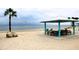 Picnic tables and chairs under a shaded area on a beach, with the ocean in the background at 4837 Rainbow Race, New Port Richey, FL 34652