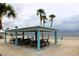 A shaded picnic area features picnic tables, chairs, and palm trees with an ocean backdrop at 4837 Rainbow Race, New Port Richey, FL 34652