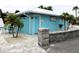 Exterior view of the bright blue beach club restroom building with tropical landscaping and brick entry at 4837 Rainbow Race, New Port Richey, FL 34652