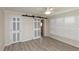 Bedroom features wood-look floors, a ceiling fan, and sliding barn doors with access to another room at 5008 Forecastle Dr, New Port Richey, FL 34652