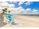 Two relaxing Adirondack chairs on the beach with a clear view of the water and palm trees at 5041 Royal Palms Way # 203, New Port Richey, FL 34652