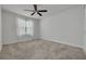 Neutral bedroom featuring carpeted floor, ceiling fan, and a window with white curtains at 5041 Royal Palms Way # 203, New Port Richey, FL 34652