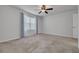 Bright bedroom with neutral carpet, ceiling fan, and a window with decorative curtains at 5041 Royal Palms Way # 203, New Port Richey, FL 34652
